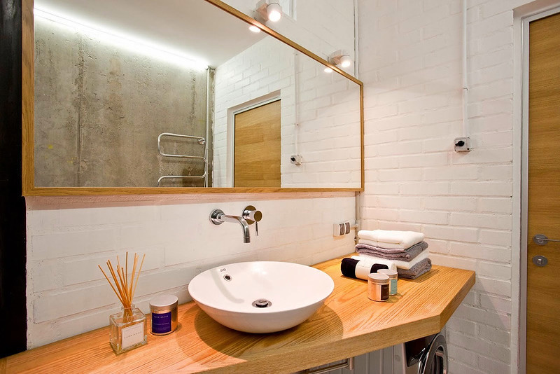 Un bagno bianco minimalista e un design a parete in mattoni