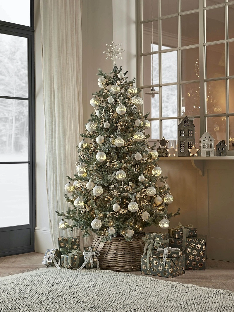 Un arbre de Noël or et blanc avec des boules et des lumières.
