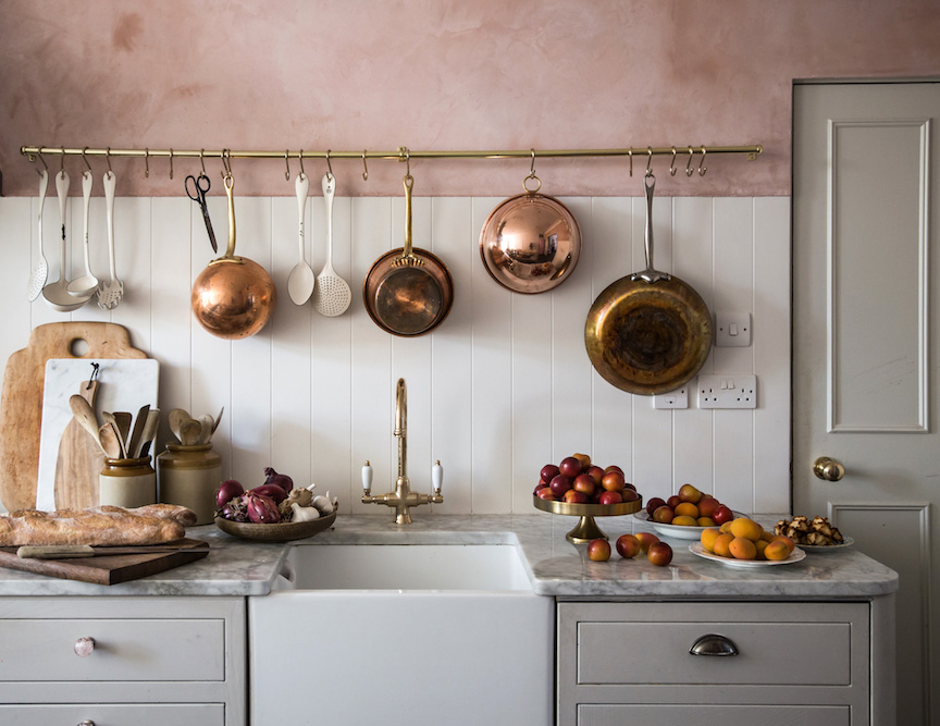 Une cuisine rose avec des éléments en cuivre