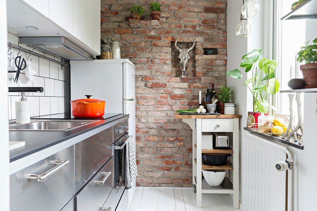 Biała wąska kuchnia - cegła na ścianie